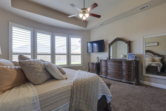bedroom featuring a raised ceiling, carpet floors, baseboards, and a ceiling fan