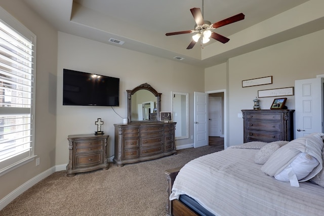 carpeted bedroom with baseboards, a tray ceiling, and ceiling fan