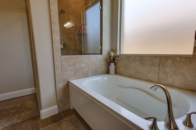 bathroom with wood finished floors and a bath