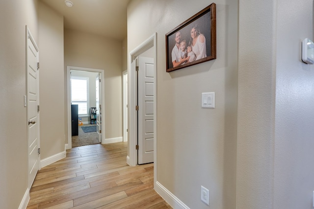 corridor featuring light wood-type flooring and baseboards