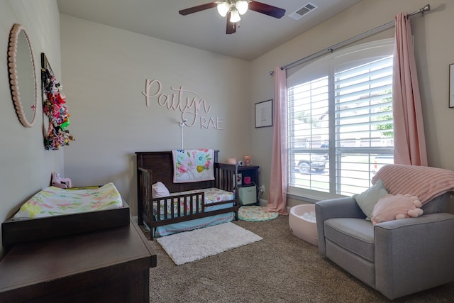 bedroom with a crib, multiple windows, carpet flooring, and ceiling fan