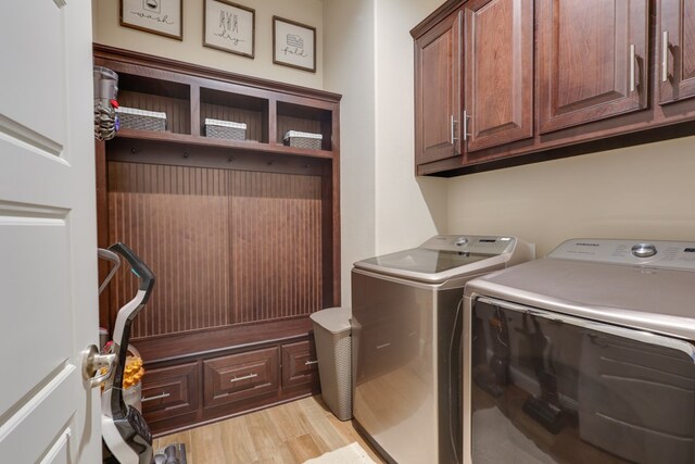washroom with cabinet space, washer and dryer, and light wood finished floors