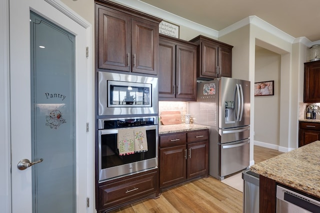 kitchen featuring stainless steel appliances, light wood finished floors, tasteful backsplash, dark brown cabinetry, and crown molding
