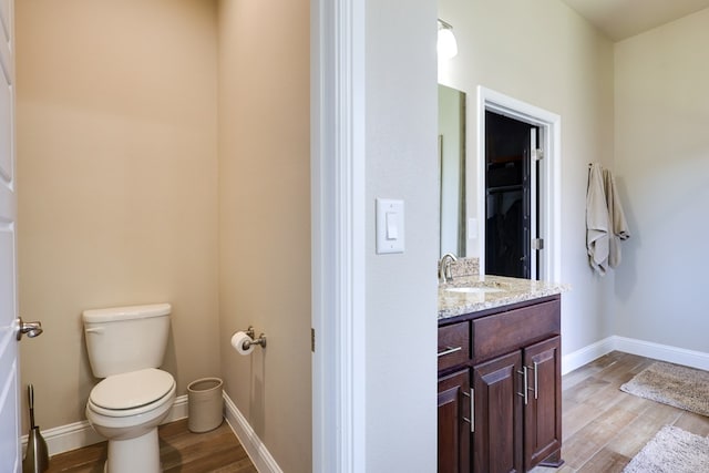 bathroom featuring wood finished floors, toilet, baseboards, and vanity