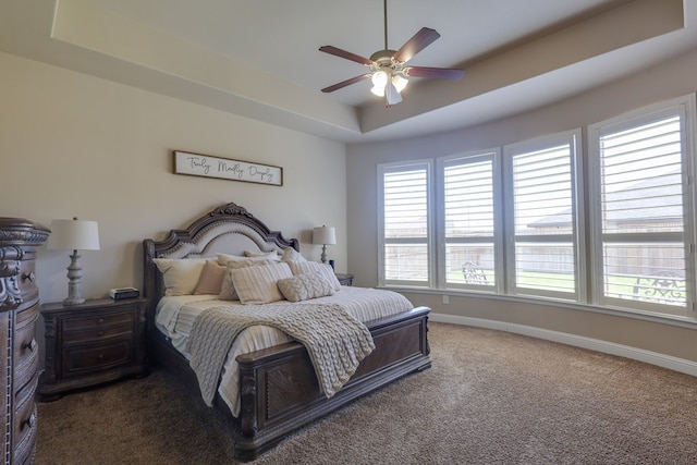 bedroom with carpet floors, multiple windows, a raised ceiling, and baseboards