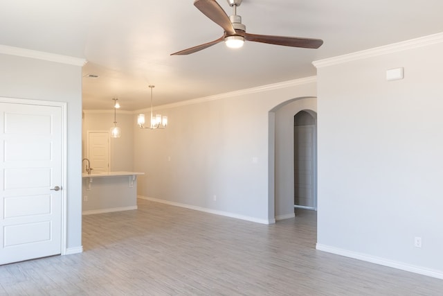 5312 Kilyn Ct, Midland, TX 79703 - unfurnished living room featuring arched walkways, crown molding, a ceiling fan, baseboards, and light wood-type flooring