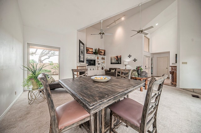 dining room featuring ceiling fan, high vaulted ceiling, and light carpet