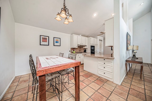 kitchen with gas cooktop, backsplash, decorative light fixtures, white cabinetry, and lofted ceiling