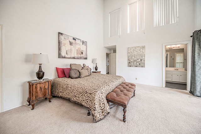 carpeted bedroom with ensuite bathroom, a towering ceiling, and sink