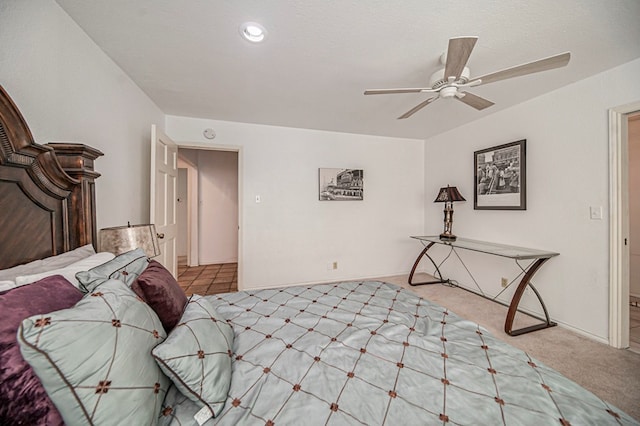 bedroom with ceiling fan, light colored carpet, and a textured ceiling