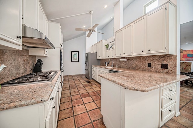 kitchen featuring white cabinets, kitchen peninsula, backsplash, and vaulted ceiling