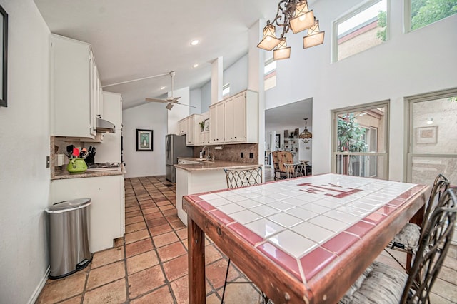 dining space featuring ceiling fan with notable chandelier, a high ceiling, and a wealth of natural light