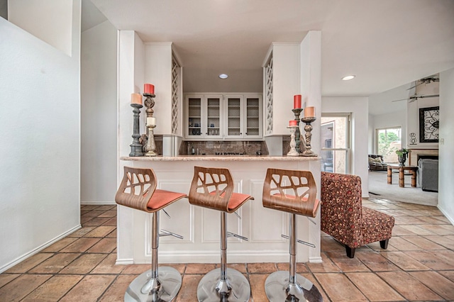 kitchen with a kitchen breakfast bar, kitchen peninsula, white cabinetry, and tasteful backsplash