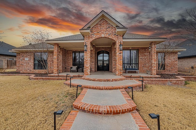 view of front of home featuring french doors and a lawn