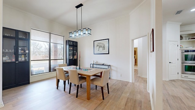 dining room featuring crown molding and light hardwood / wood-style floors