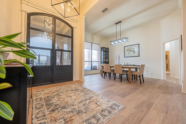 foyer entrance featuring an inviting chandelier, crown molding, wood-type flooring, and french doors