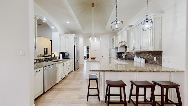 kitchen with stainless steel appliances, kitchen peninsula, sink, and white cabinets