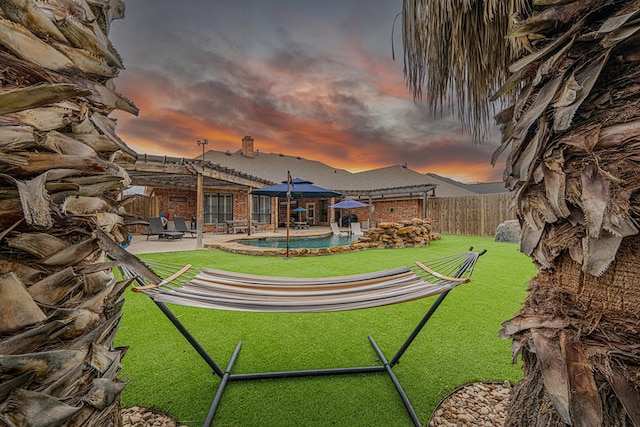 yard at dusk with a fenced in pool and a patio area