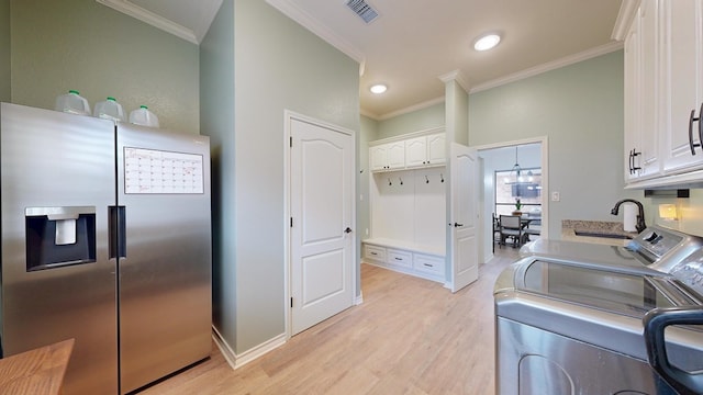 kitchen featuring sink, light hardwood / wood-style flooring, washing machine and dryer, stainless steel refrigerator with ice dispenser, and white cabinets