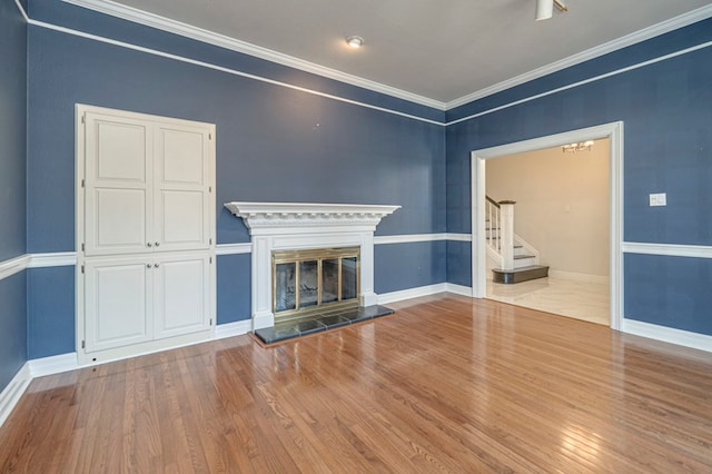 unfurnished living room featuring a fireplace, ornamental molding, and hardwood / wood-style flooring