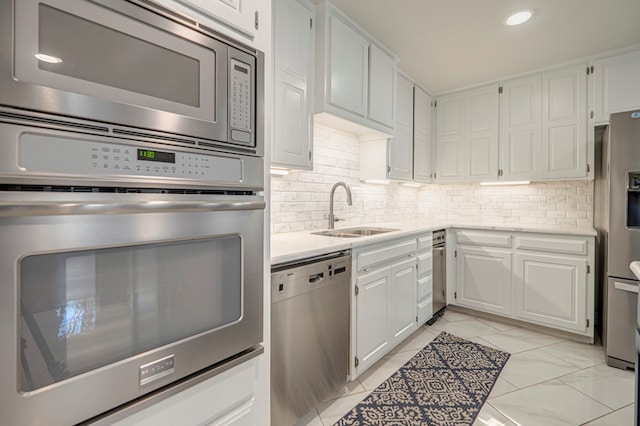 kitchen featuring backsplash, white cabinetry, sink, and appliances with stainless steel finishes