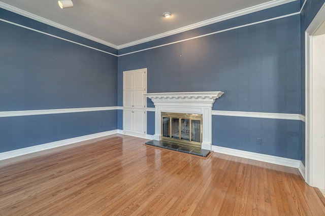 unfurnished living room with a tiled fireplace, crown molding, and wood-type flooring