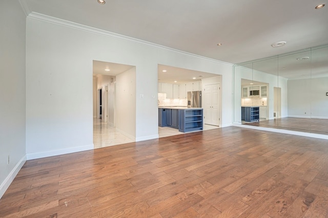 unfurnished living room featuring crown molding and light hardwood / wood-style flooring