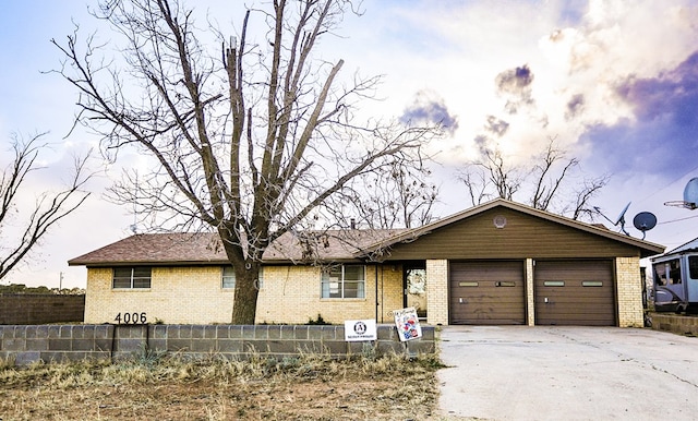 ranch-style home featuring brick siding, concrete driveway, a garage, and fence