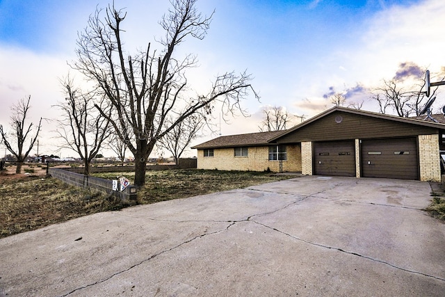 view of front of house featuring brick siding, fence, a garage, and driveway