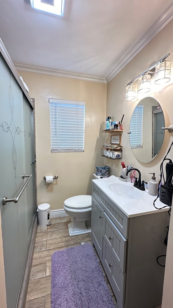 bathroom featuring hardwood / wood-style flooring, ornamental molding, and a shower with door