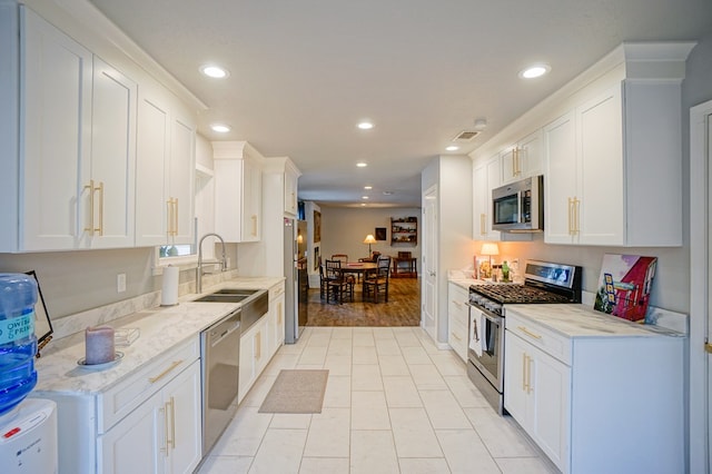 kitchen with white cabinetry, sink, light stone countertops, and appliances with stainless steel finishes