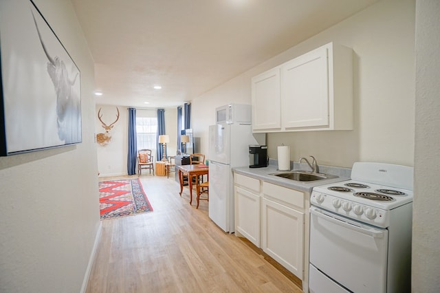 kitchen with sink, white appliances, white cabinets, and light wood-type flooring