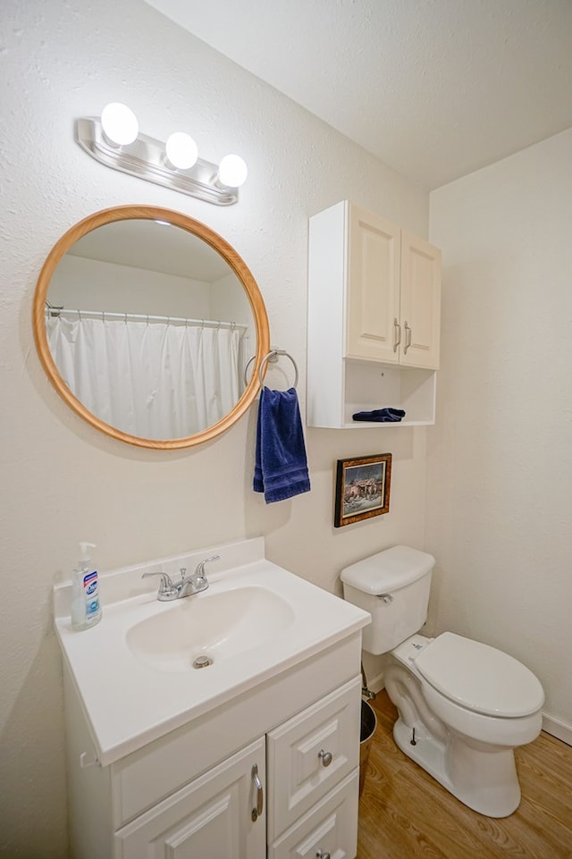 bathroom with hardwood / wood-style flooring, vanity, toilet, and curtained shower