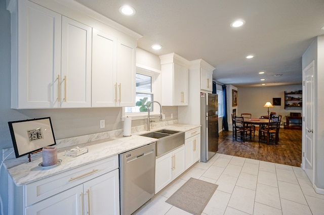 kitchen featuring sink, dishwasher, fridge, light stone counters, and white cabinets