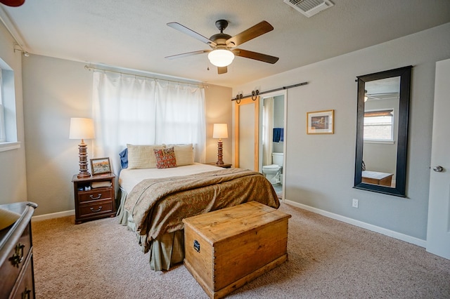 carpeted bedroom with ceiling fan, a barn door, a textured ceiling, and ensuite bathroom