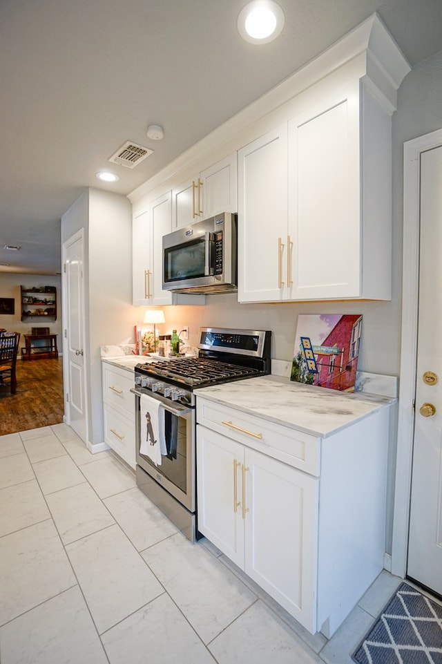 kitchen featuring white cabinetry, light tile patterned floors, light stone countertops, and appliances with stainless steel finishes