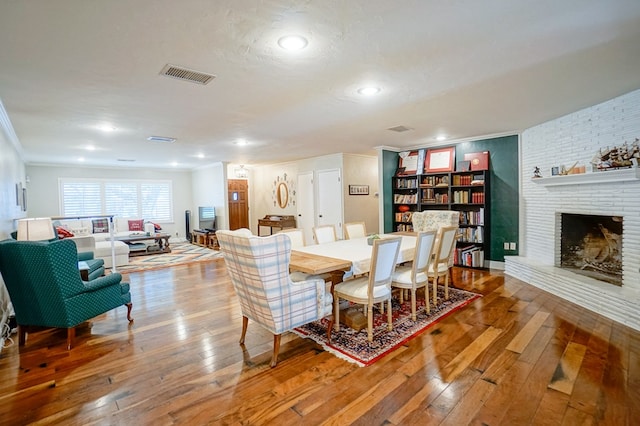 dining room featuring a fireplace, wood-type flooring, and crown molding