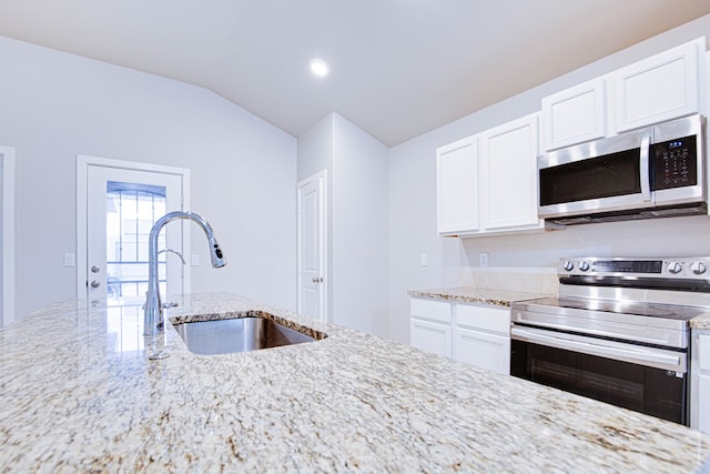 307 Pioneer Cir, Midland, TX 79705 - kitchen with stainless steel appliances, light stone countertops, white cabinets, lofted ceiling, and recessed lighting