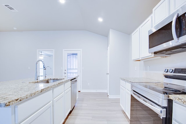 307 Pioneer Cir, Midland, TX 79705 - kitchen with stainless steel appliances, light wood-style floors, white cabinetry, vaulted ceiling, and light stone countertops