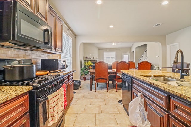 kitchen with black appliances, light stone counters, light tile patterned floors, and sink