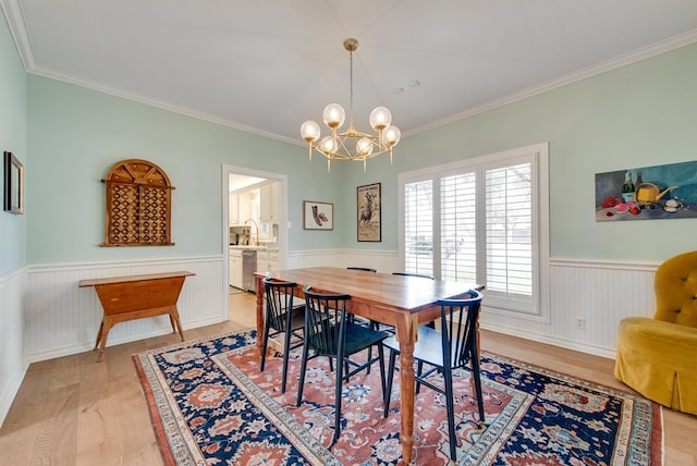 dining space featuring crown molding, an inviting chandelier, and light wood-type flooring