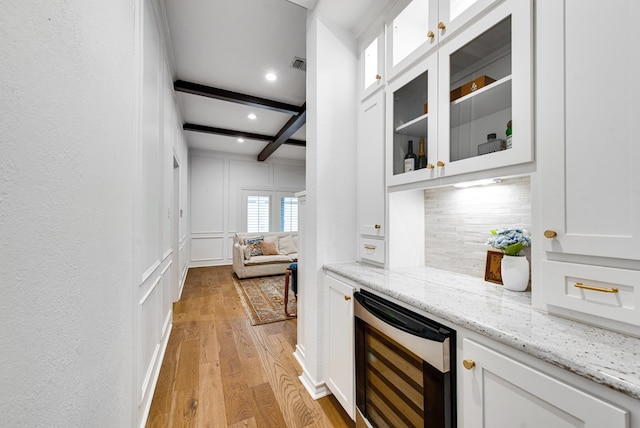 bar featuring white cabinets, light wood-type flooring, beverage cooler, and light stone counters