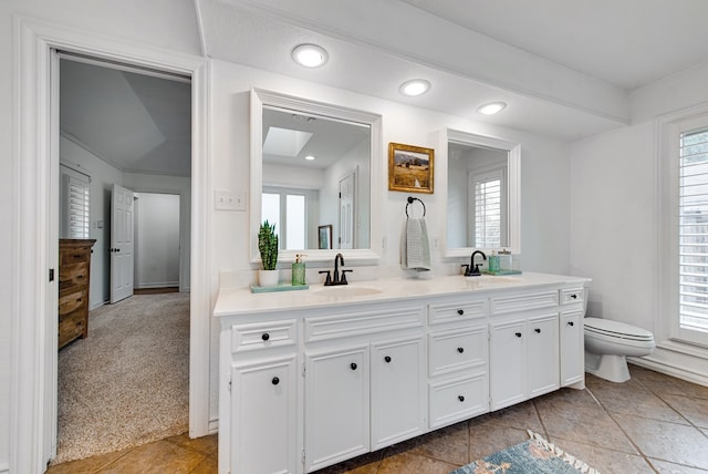 bathroom with a skylight, vanity, and toilet