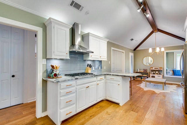 kitchen with stainless steel gas stovetop, white cabinets, light hardwood / wood-style floors, light stone counters, and wall chimney exhaust hood