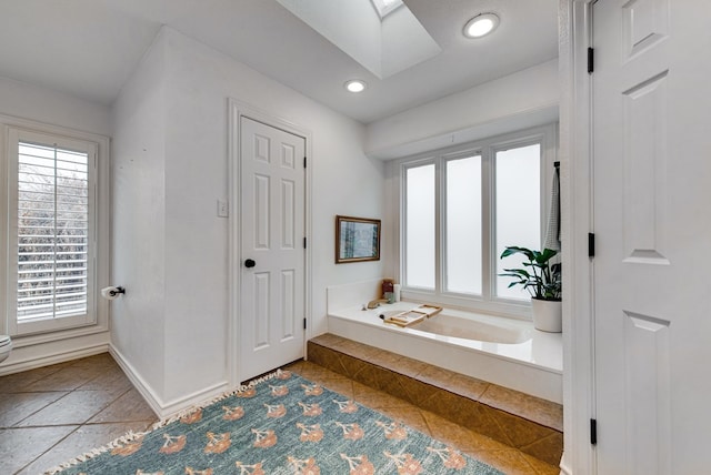 bathroom with a relaxing tiled tub and a skylight