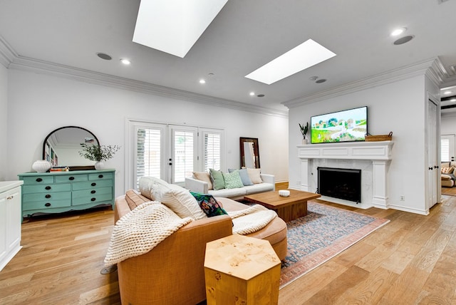 living room with ornamental molding, a premium fireplace, a skylight, and light hardwood / wood-style floors