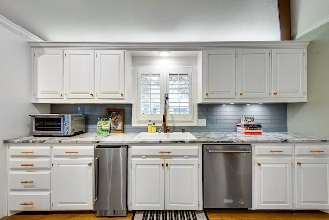 kitchen with tasteful backsplash, sink, light stone countertops, and white cabinets