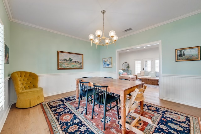 dining room with an inviting chandelier, hardwood / wood-style floors, and crown molding