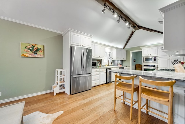 kitchen featuring light stone counters, a kitchen bar, white cabinets, and appliances with stainless steel finishes