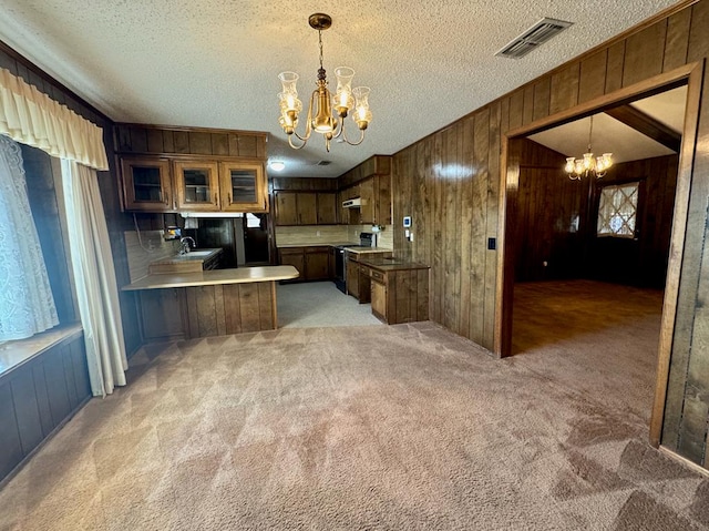 kitchen featuring decorative light fixtures, light colored carpet, kitchen peninsula, and a chandelier